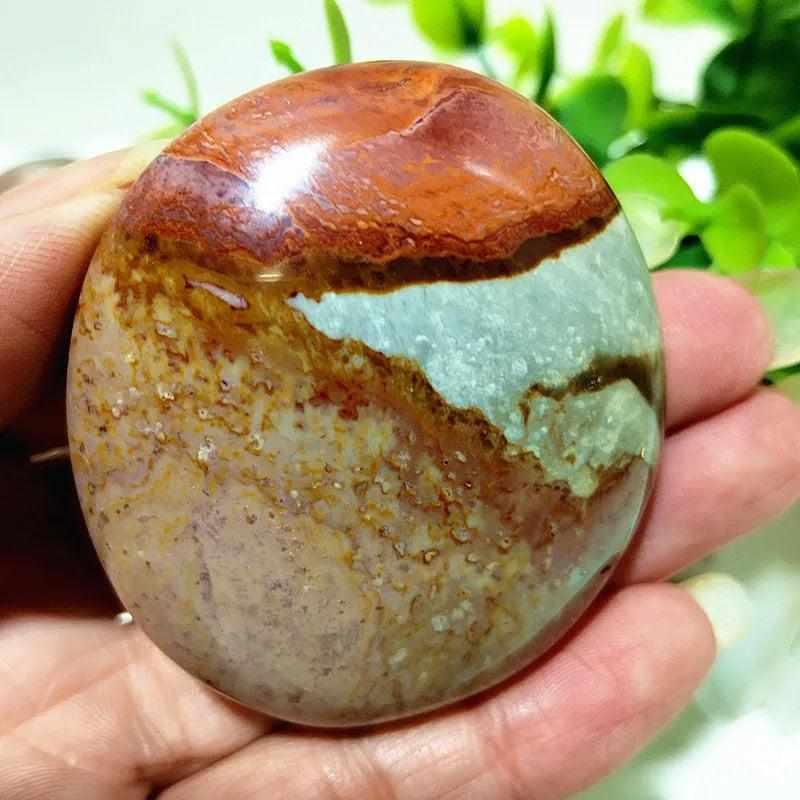 Polished polychrome jasper palm stone with earthy rust, cream, and sage bands for grounding meditation and chakra healing.