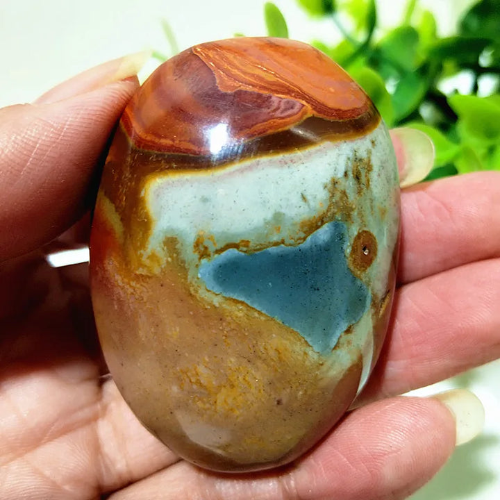 Polished polychrome jasper palm stone featuring earthy rust, cream, and sage bands for grounding meditation energy.