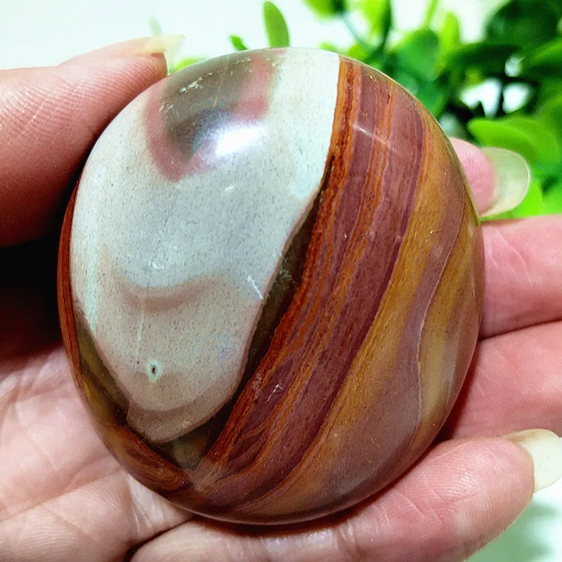 Polished polychrome jasper palm stone with rust, cream, and ochre bands for grounding meditation and chakra healing.