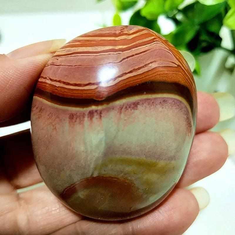 Polished polychrome jasper palm stone with earthy rust, cream, and sage bands for grounding meditation and energy.