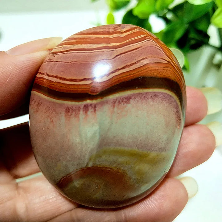 Polished polychrome jasper palm stone with earthy rust, cream, and sage bands for grounding meditation and energy.