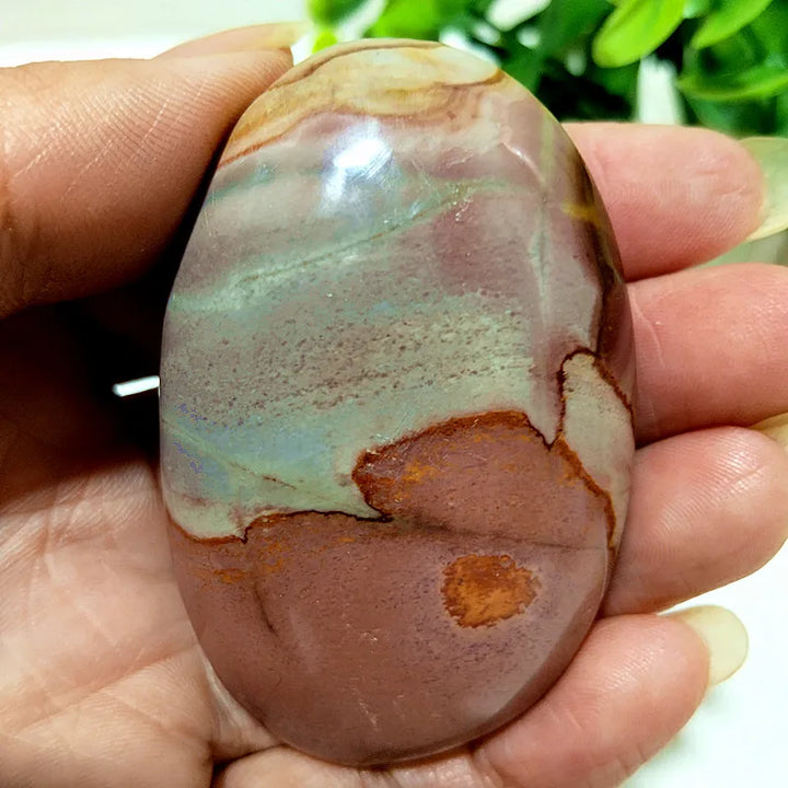 Polished polychrome jasper palm stone with earthy bands of rust, cream, and sage for grounding and chakra healing.