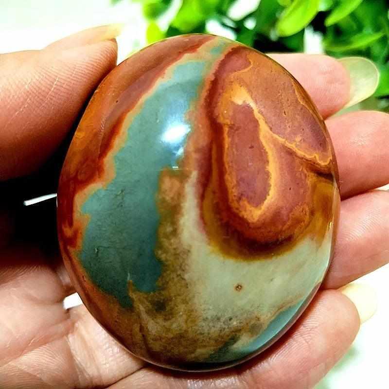 Polished Polychrome Jasper palm stone with swirling rust, cream, and sage bands for grounding and chakra meditation.