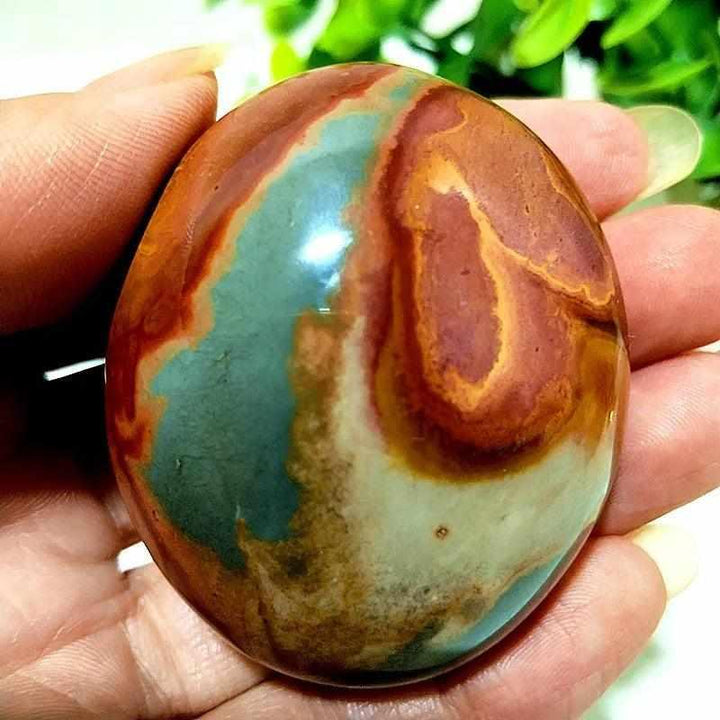 Polished Polychrome Jasper palm stone with swirling rust, cream, and sage bands for grounding and chakra meditation.