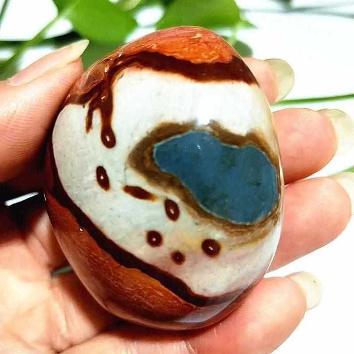 Polished polychrome jasper palm stone with earthy rust, cream, and sage bands for grounding and chakra meditation.