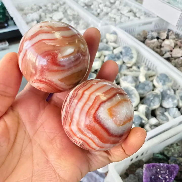 Two polished natural Rhodochrosite crystal balls featuring vibrant red and white banded patterns for healing and decor.