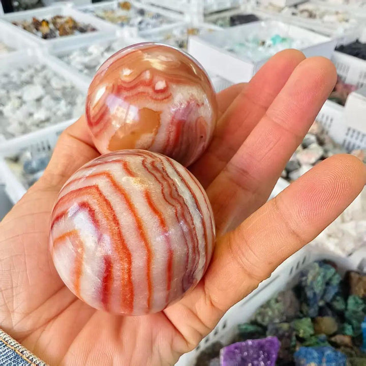 Two polished natural Rhodochrosite crystal balls with vibrant pink and white banded patterns for healing and home decor.