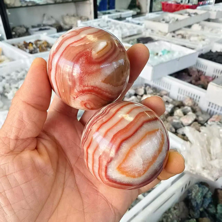 Two polished natural Rhodochrosite crystal balls featuring vibrant red and white banded patterns for healing and decor.