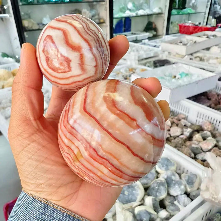 Polished natural Rhodochrosite crystal balls with beautiful pink and white banded patterns for healing and home decor.