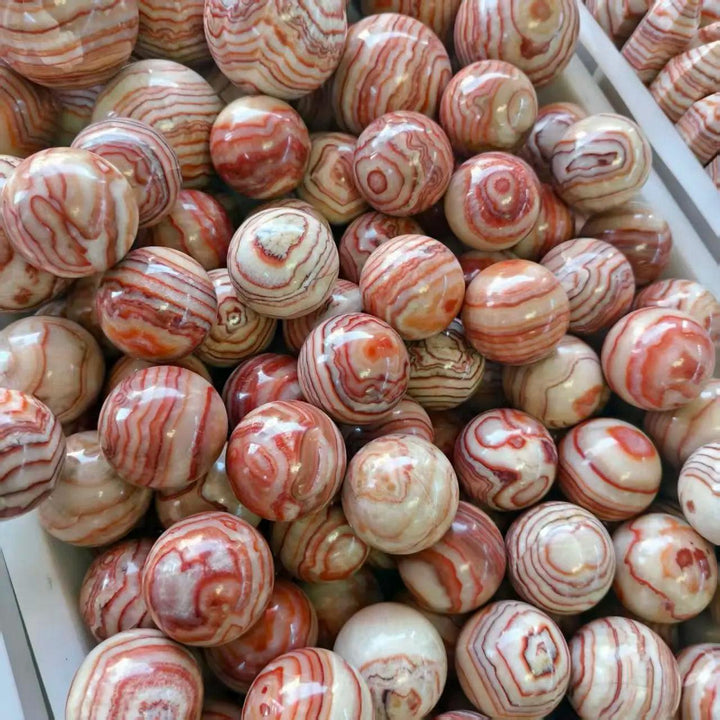 Polished natural Rhodochrosite balls featuring beautiful red and white banded patterns for healing and mineral collection.