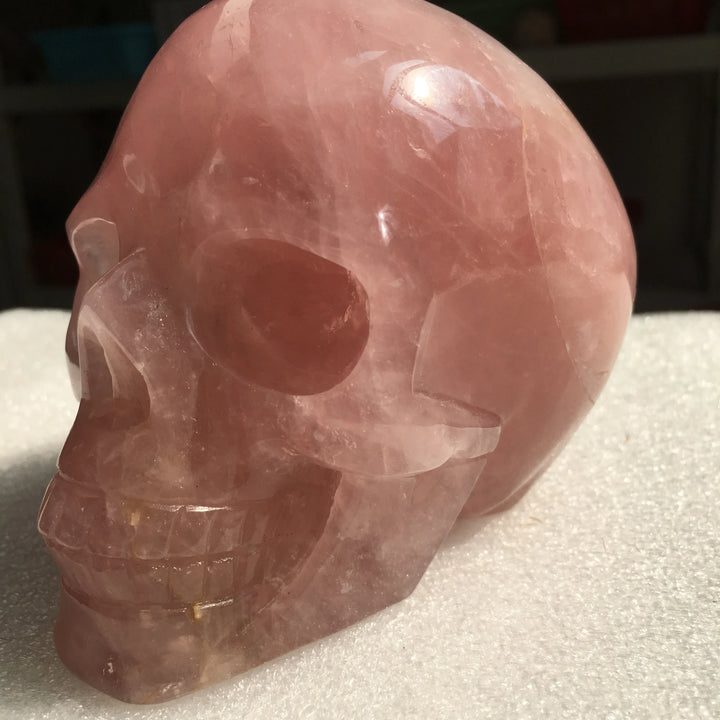 Hand-carved rose quartz crystal skull for Reiki healing, featuring a polished, translucent pink finish for home decor.
