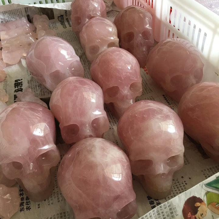 Hand-carved rose quartz crystal skulls with a polished pink finish, perfect for Reiki healing and unique home decor.