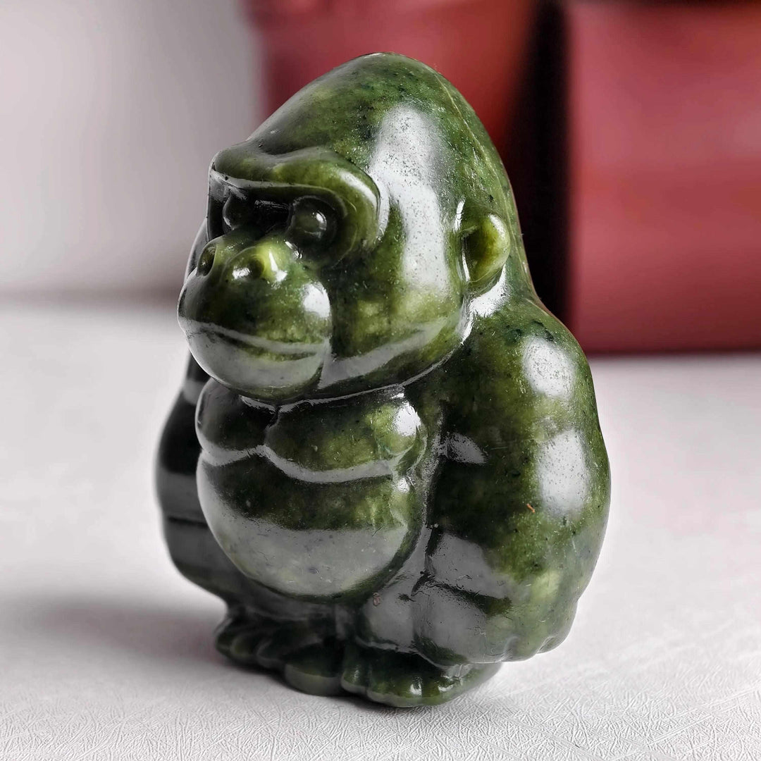 Polished natural serpentine gorilla sculpture in deep olive green, perfect for grounding energy and heart chakra healing.