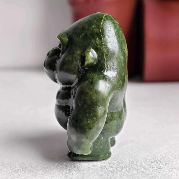 Polished olive-green Serpentine crystal carved into a grounded gorilla sculpture for Heart Chakra healing and protection.