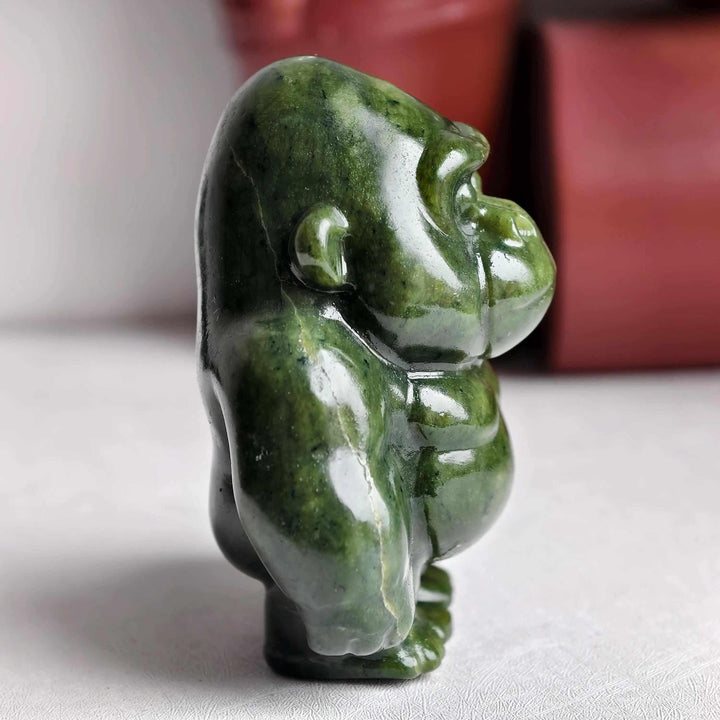 Polished natural serpentine crystal gorilla sculpture in deep olive green, offering grounding energy and heart chakra calm.