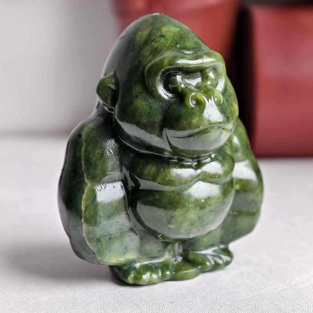 Polished natural serpentine gorilla sculpture in deep olive green, offering grounding energy and heart chakra healing.