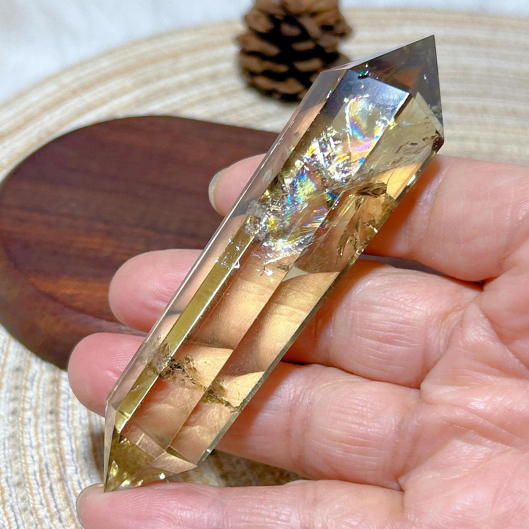 Hand holding a natural smokey citrine double tower crystal with rainbow inclusions, ideal for energy healing.