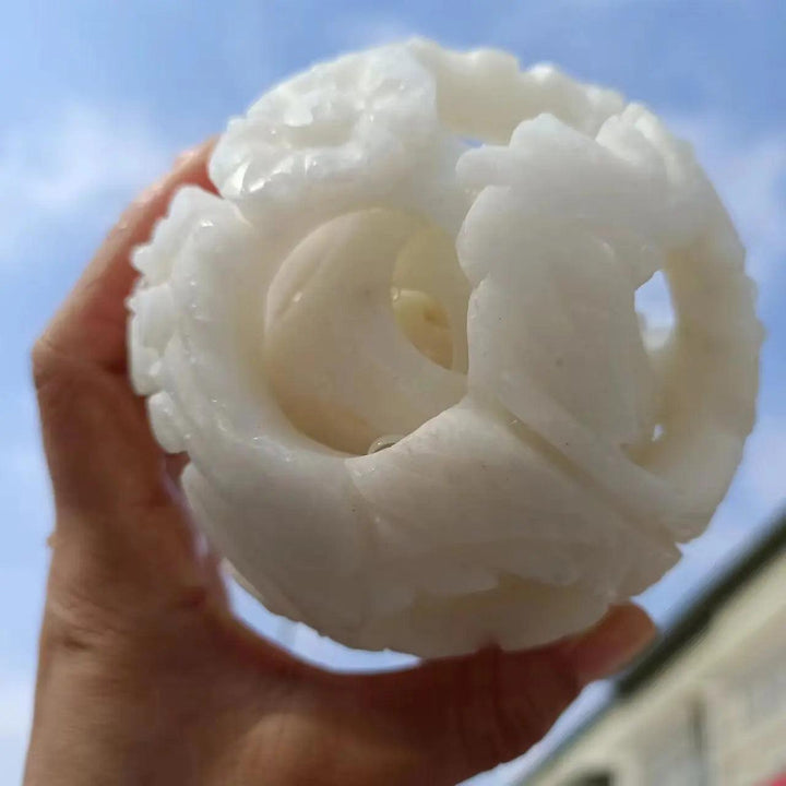 Hand-carved natural white jade ball with intricate floral patterns, perfect for reiki healing and energy divination.