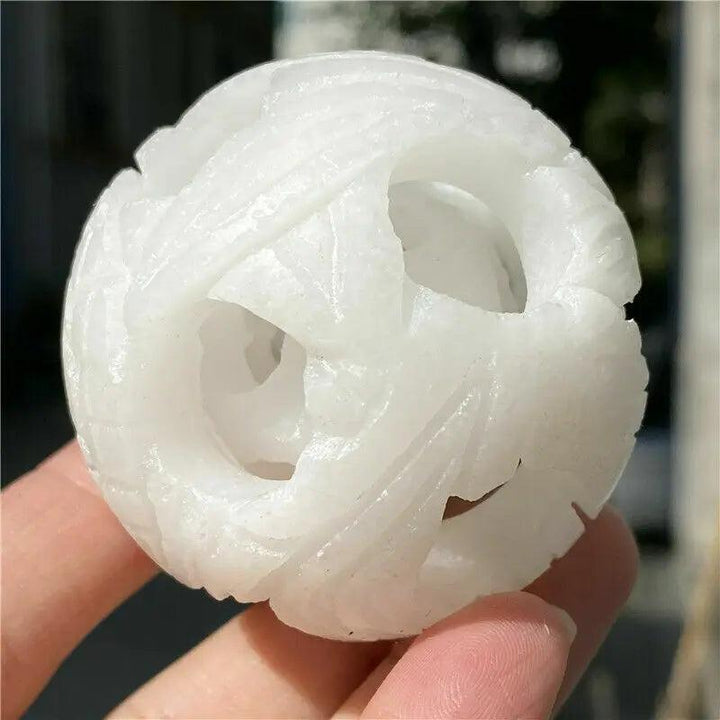 Hand-carved Natural White Jade ball with intricate cutouts for Reiki healing, energy balancing, and spiritual decor.