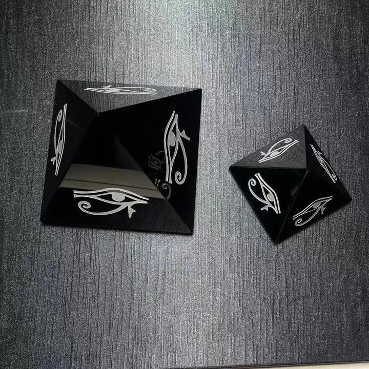 Polished black obsidian crystal pyramids featuring hand-engraved Eye of Horus symbols for protection and grounding.