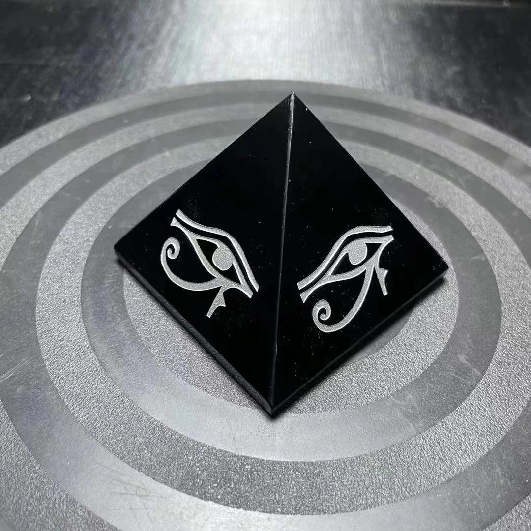 Polished black Obsidian crystal pyramid featuring a protective hand-engraved Eye of Horus symbol for grounding energy.