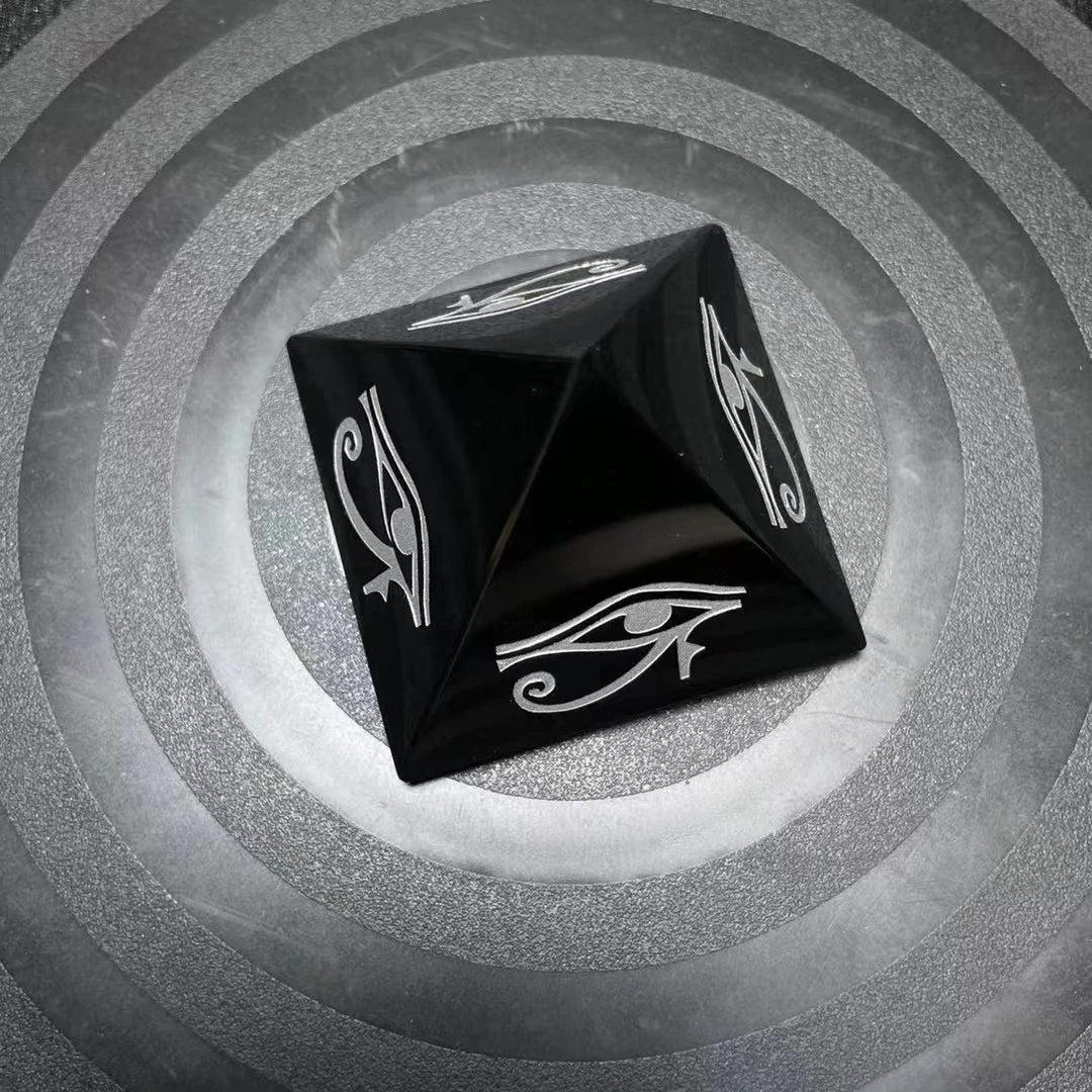 Polished black obsidian pyramid featuring a protective hand-engraved Eye of Horus symbol for grounding and energy shielding.