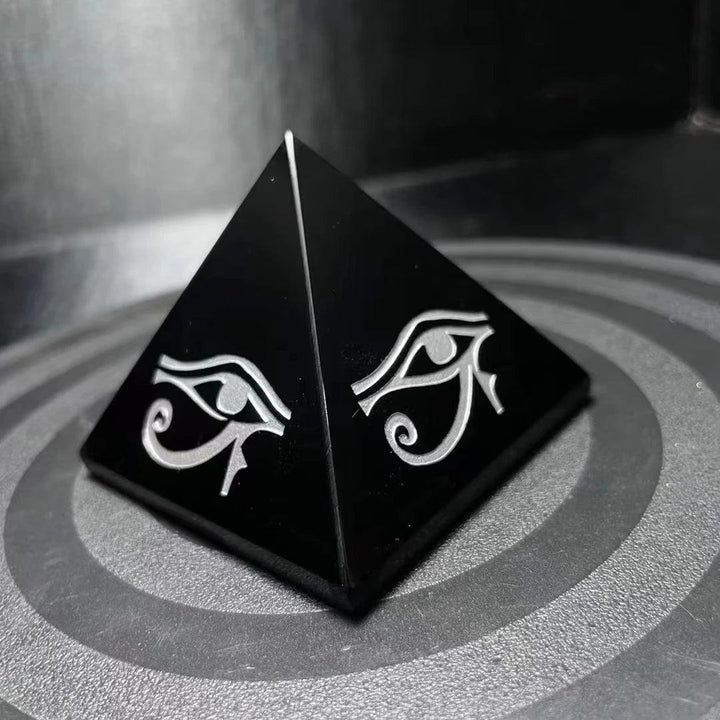 Polished black obsidian pyramid featuring hand-engraved Eye of Horus symbols for powerful energetic protection.