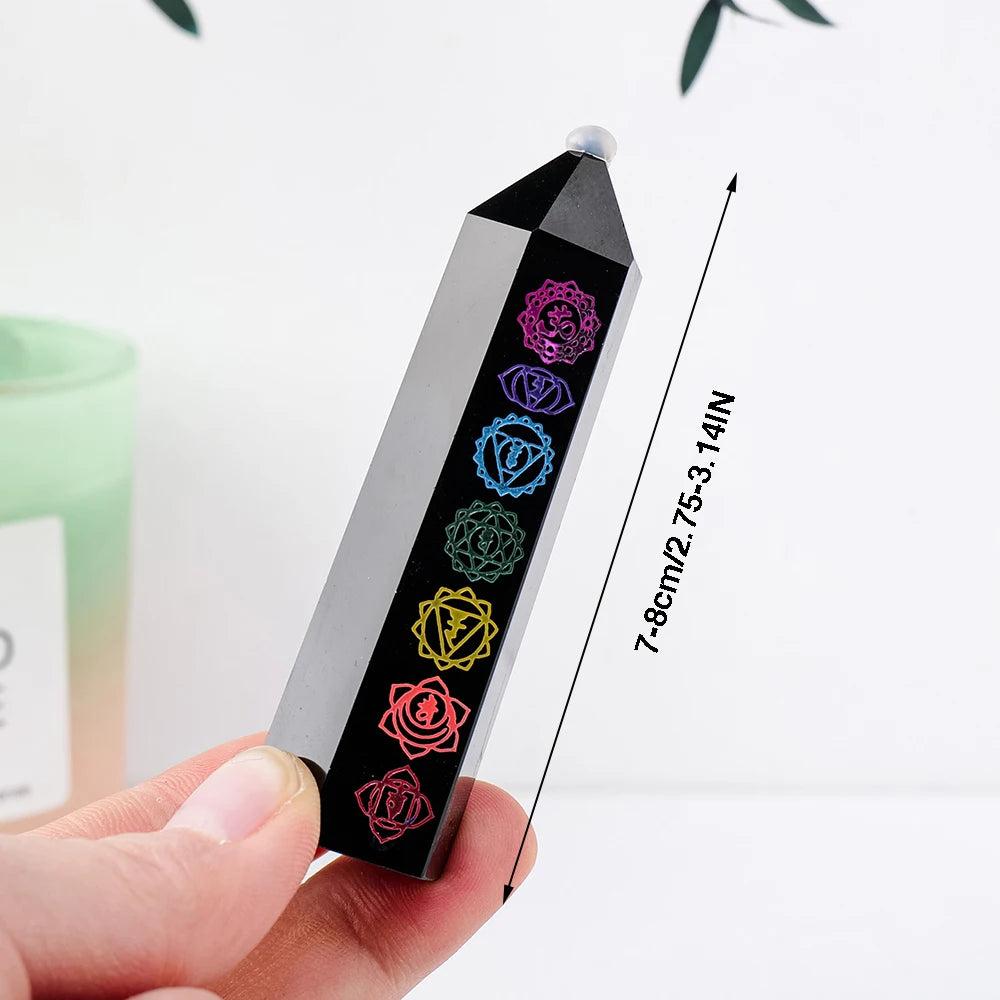 Natural black obsidian crystal tower with engraved colorful chakra symbols for energy healing and Feng Shui decor.