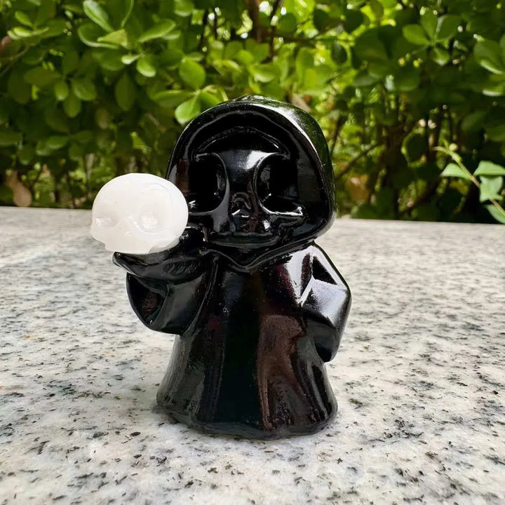 Polished black obsidian ghost skull figurine holding a white crystal skull for healing and spooky Halloween home decor.