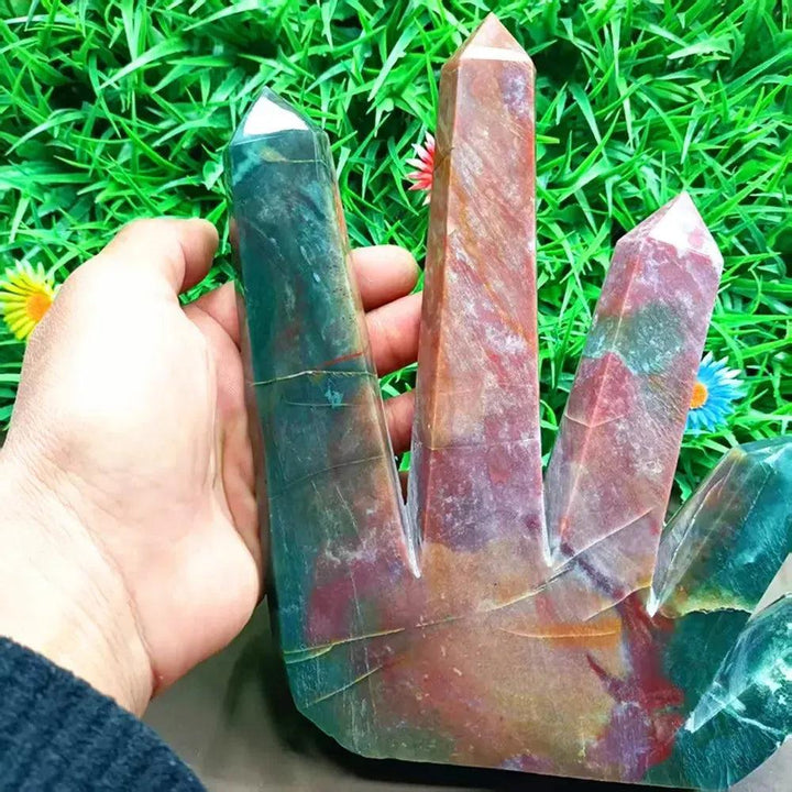 Large Ocean Jasper 5-point crystal tower in green, cream, pink, and rust, held against green grass.