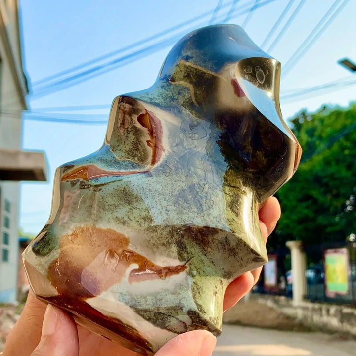 Polished Ocean Jasper flame freeform, showcasing green, brown, and cream orbicular patterns, held outdoors.