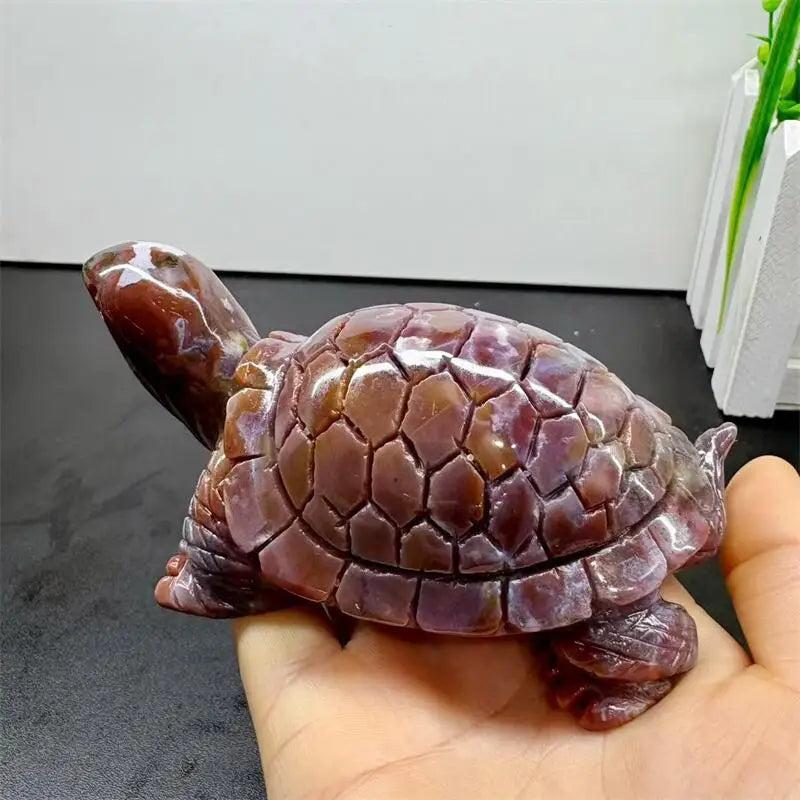 Hand-carved Ocean Jasper turtle with swirling cream, sage, rust, and seafoam colors, held in a palm.
