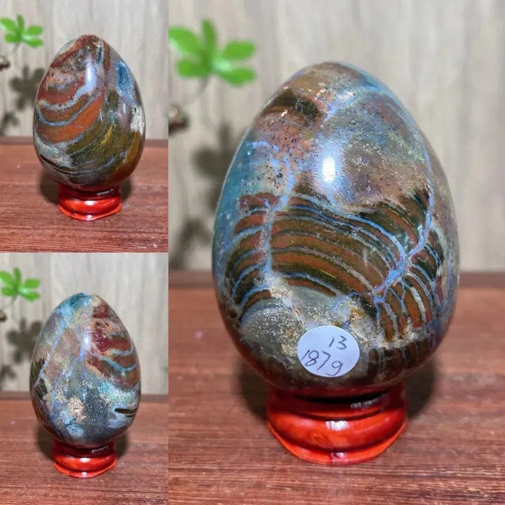 Polished Ocean Jasper crystal egg from Crystal Destiny, featuring unique green, pink, and brown orb patterns on a red stand.