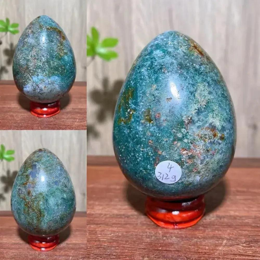 Ocean Jasper crystal egg from Crystal Destiny, featuring swirling greens, browns, and blues on a red stand.