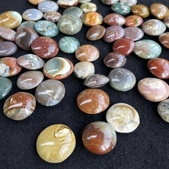 Polished, colorful Ocean Jasper palm stones in earthy red, green, and yellow tones for home decor.