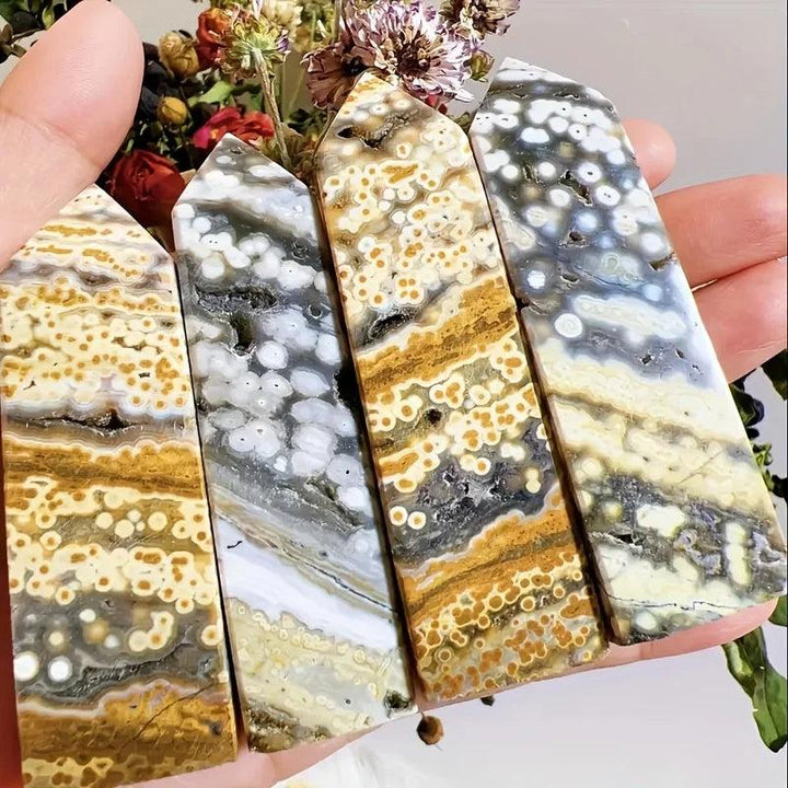 Four polished Ocean Jasper crystal towers with orbicular patterns in cream, gold, gray, and white.