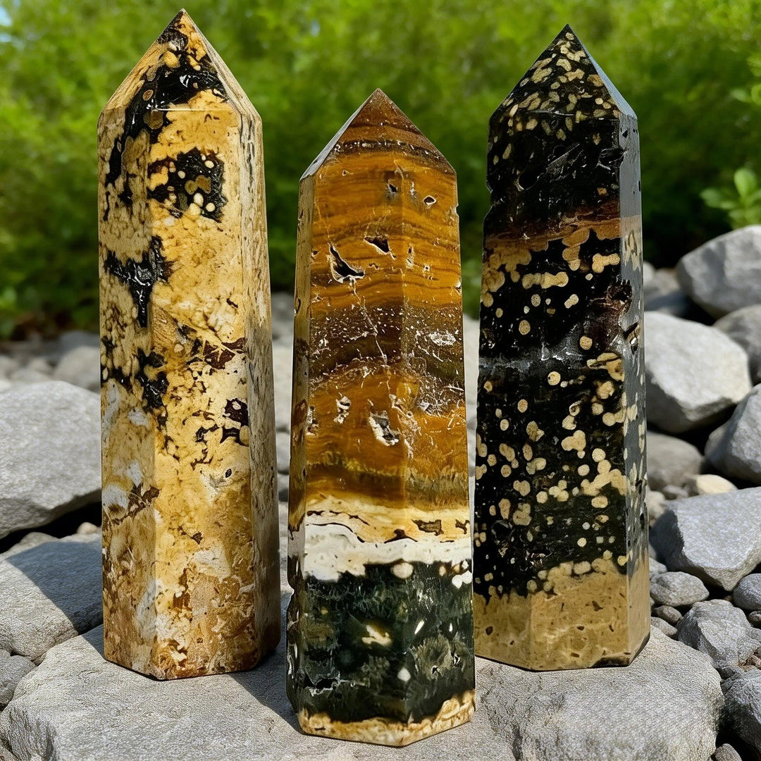 Three natural Ocean Jasper crystal pillars in earthy yellow, brown, and black patterns.