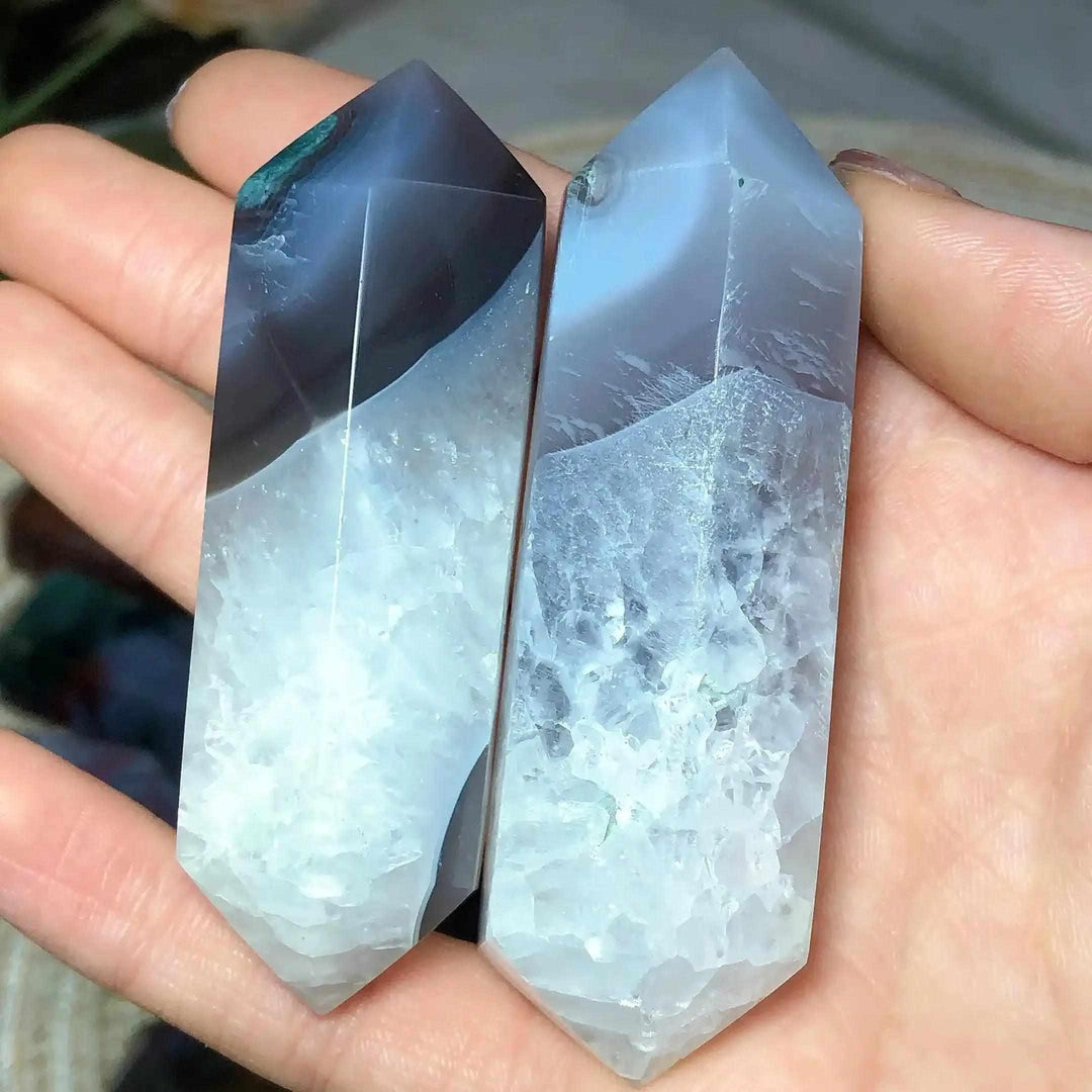 Polished Ocean Jasper double point tower with blue-grey banding and crystalline textures held in a palm for healing.