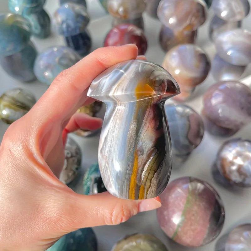 Hand holding a polished Ocean Jasper mushroom crystal carving with sage, cream, and rust swirls, promoting joy and calm.