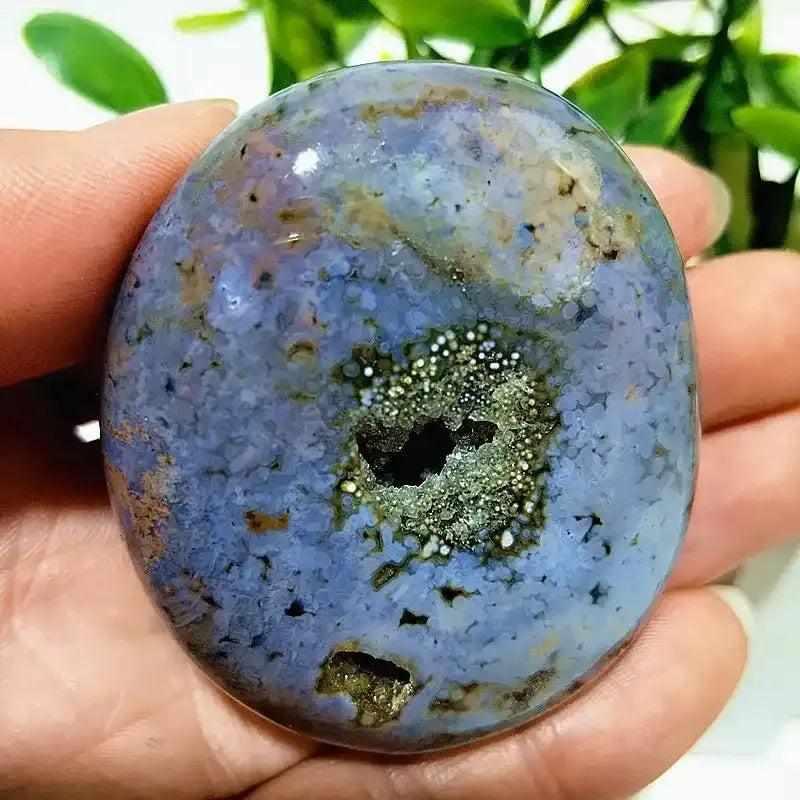 Smooth Ocean Jasper palm stone with blue, cream, and green orbs, featuring a sparkling crystal druzy center for calm.