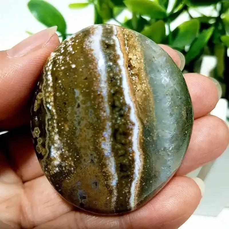 Smooth Ocean Jasper palm stone with green and cream swirls, perfect for heart chakra healing and calming meditation.