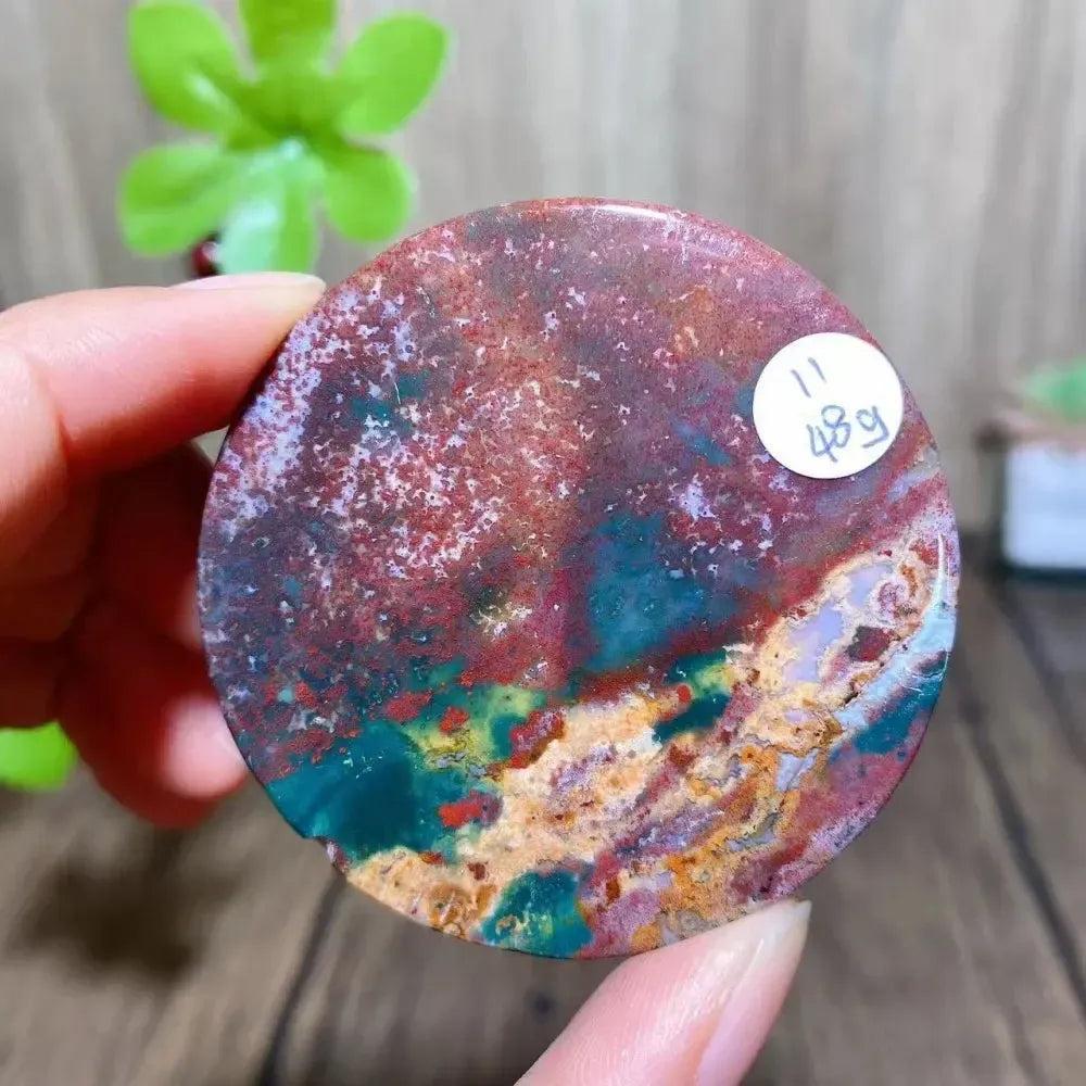 Crystal Destiny Ocean Jasper round slice, featuring vibrant reds, greens, and earthy tones with orb patterns.