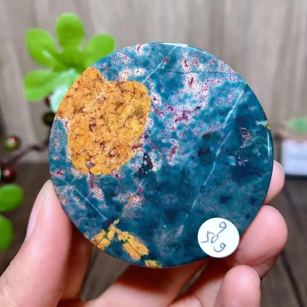 Ocean Jasper round slice from Crystal Destiny, featuring vibrant teal, orange, and red patterns.
