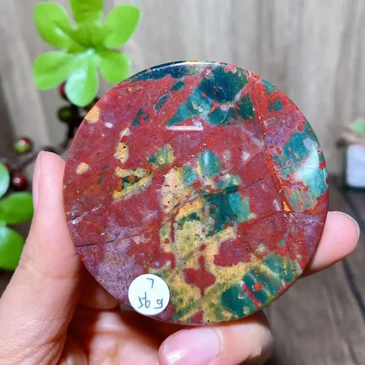 Polished Ocean Jasper round slice from Crystal Destiny, showcasing vibrant red, green, and yellow patterns.
