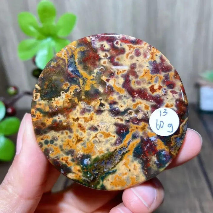 Polished Ocean Jasper round slice from Crystal Destiny, featuring vibrant reds, yellows, and greens, weighing 60g.