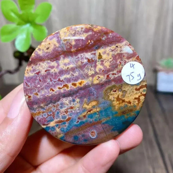 Crystal Destiny Ocean Jasper round slice with vibrant red, blue, yellow, and purple patterns.