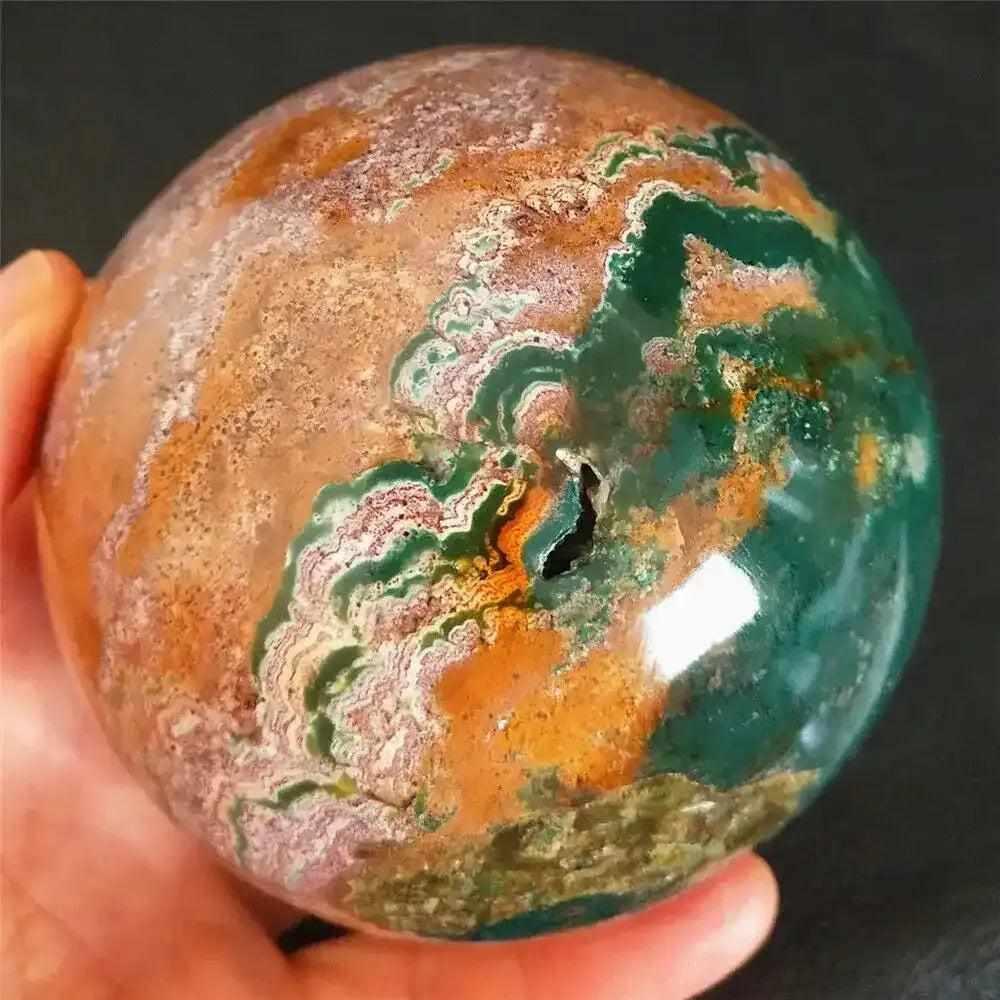 Polished Ocean Jasper sphere featuring flowing sea green, cream, and pink orb patterns for heart chakra healing.