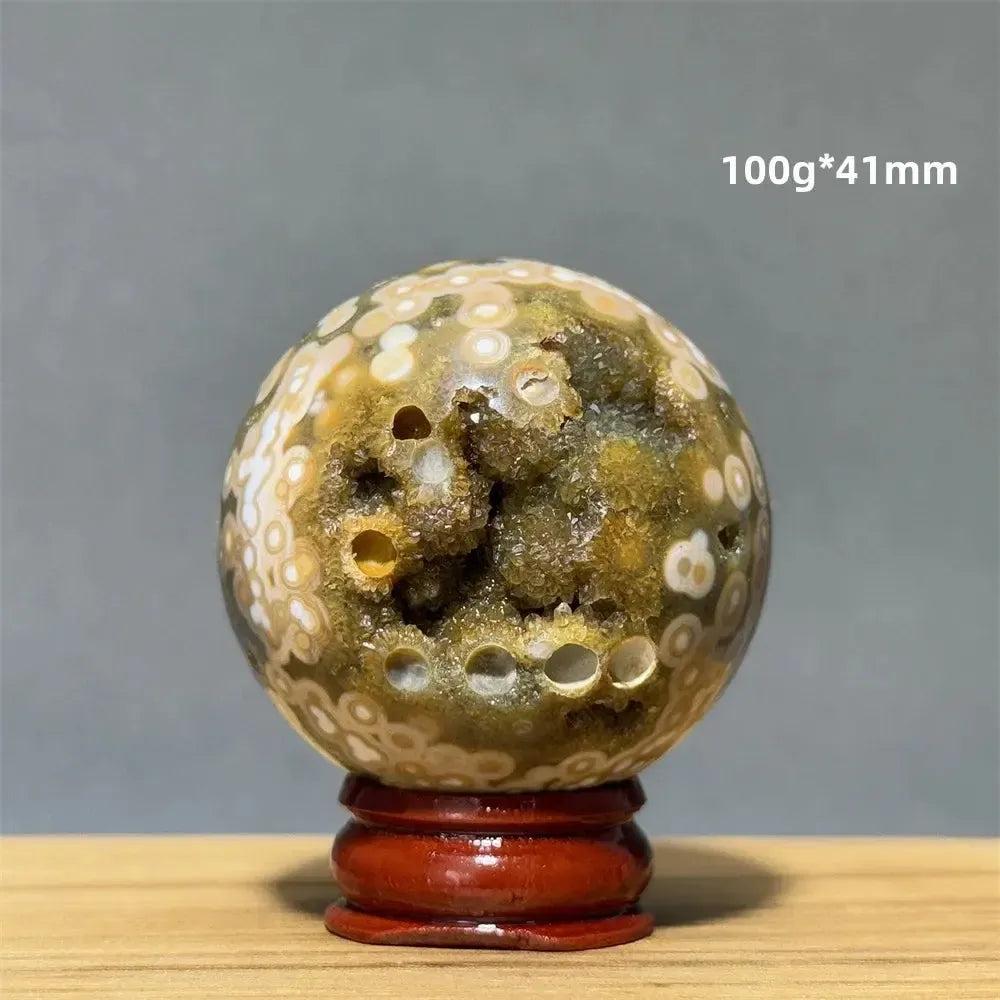 Ocean Jasper sphere with green, white, and cream orbicular patterns, 100g, 41mm, on a red wooden base.