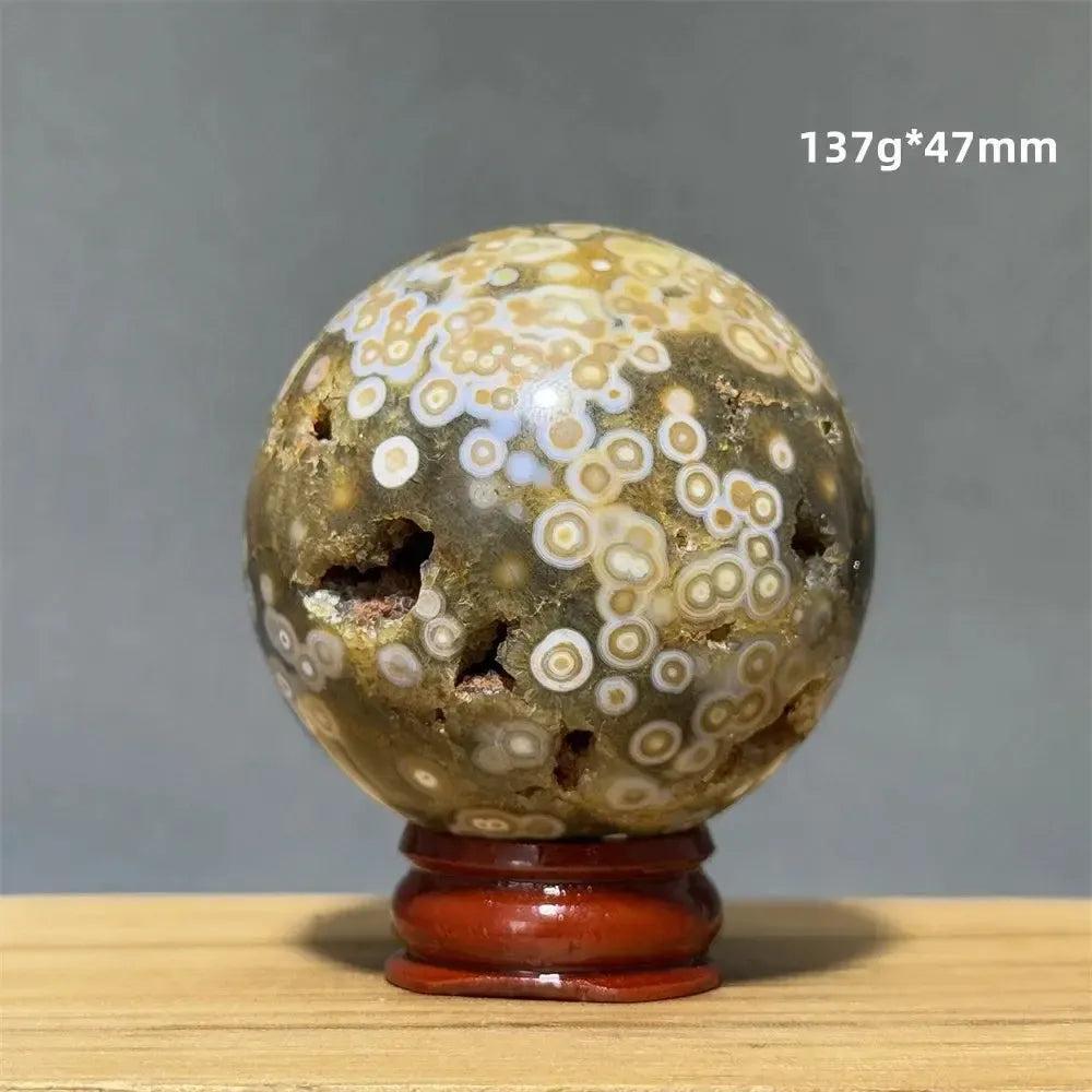 Ocean Jasper sphere from Crystal Destiny, with unique green, white, cream, pink, and red orbicular patterns on a brown base.