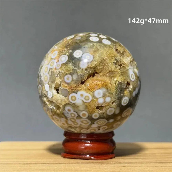 Ocean Jasper sphere from Crystal Destiny, 142g, 47mm, with green, white, cream, pink orbicular patterns on a red base.